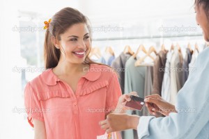 Female customer receiving credit card from saleswoman in boutique