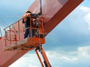 Worker welding a structural node of a steel beam on site